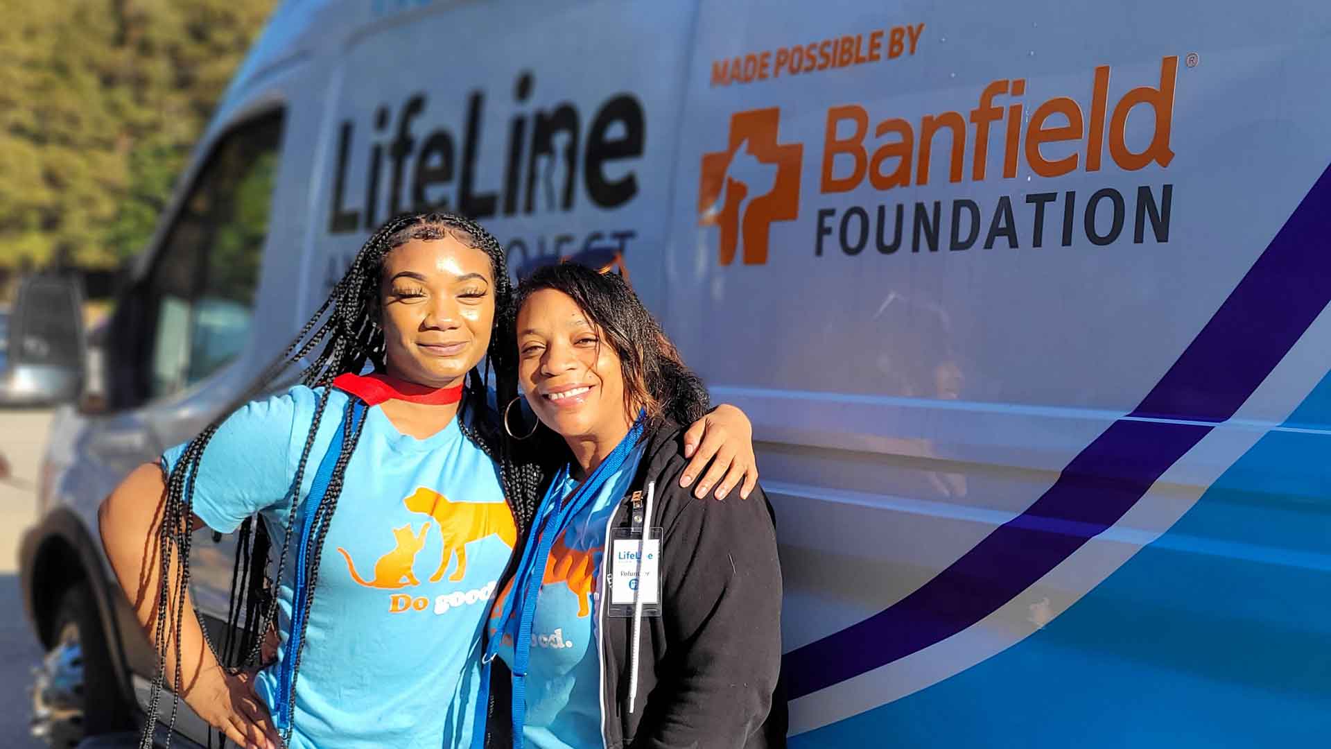 Dos asociados de pie frente a una furgoneta de la Banfield Foundation