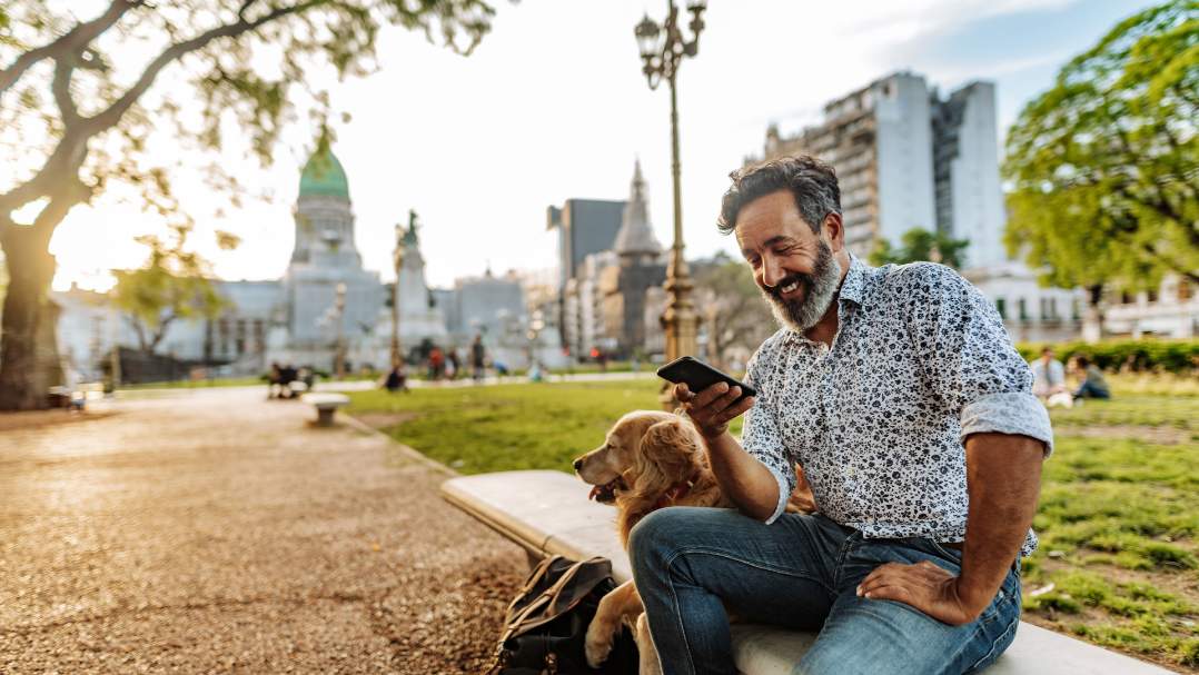 Persona con un teléfono que está sentada al aire libre junto a un perro