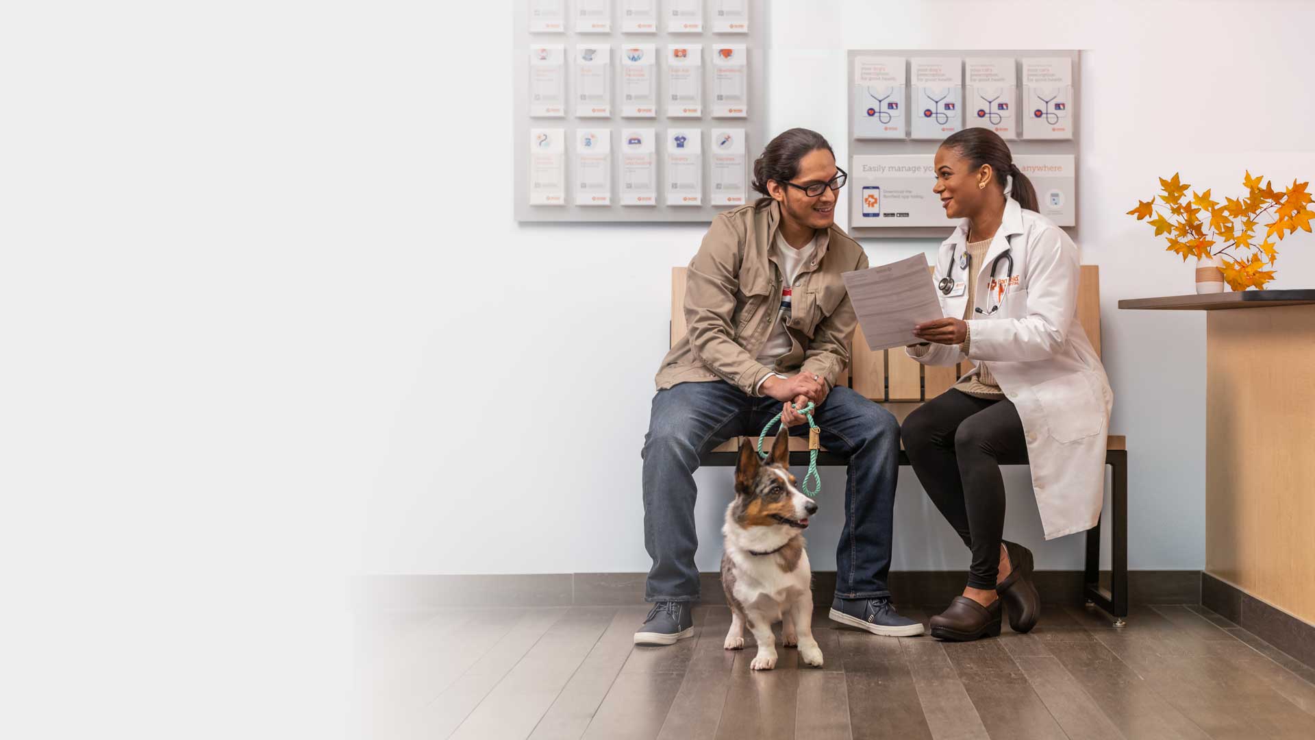 A vet discussing medical charts with a dog owner while the dog sits at his feet