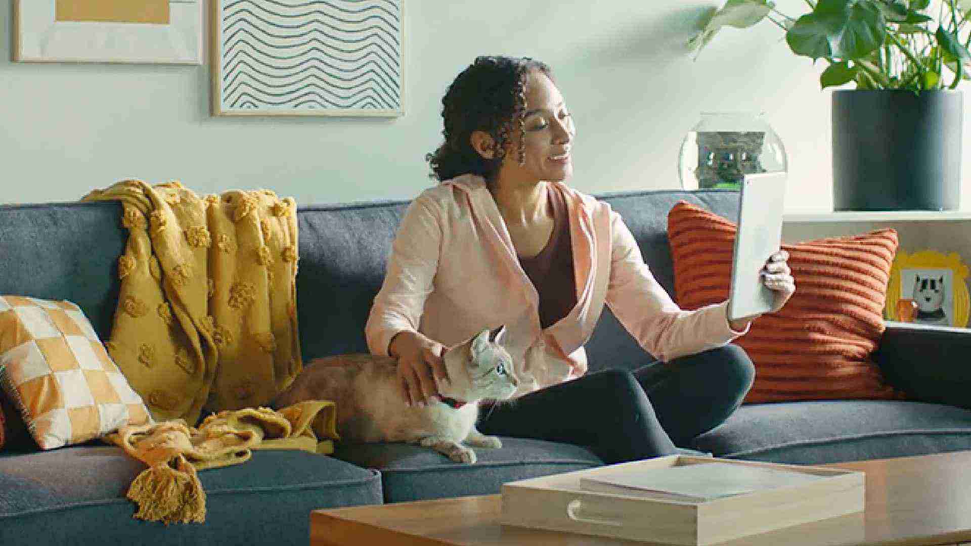 mujer con su gato y una tableta en un sofá