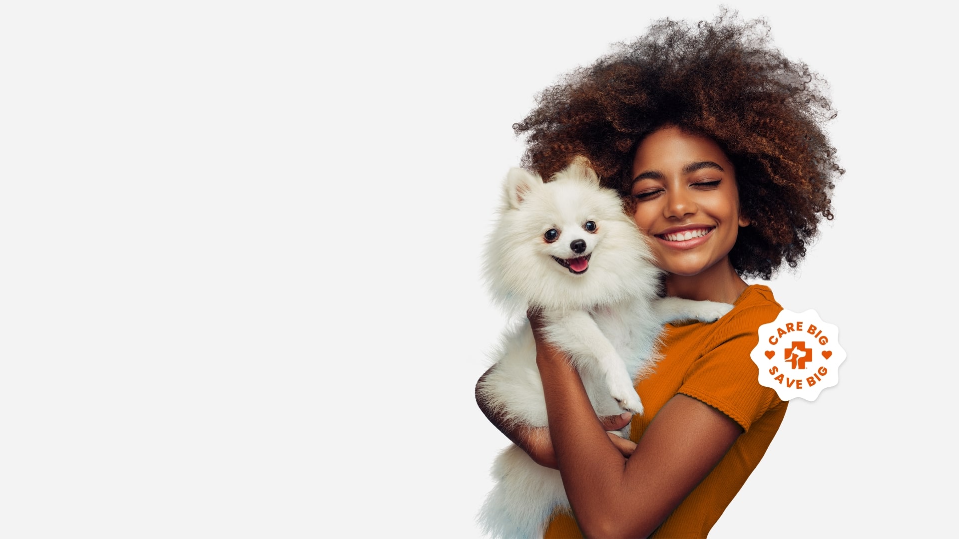 Una mujer con camiseta naranja abrazando a un perro pequeño