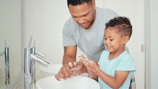 Un hombre ayuda a un niño pequeño a lavarse las manos