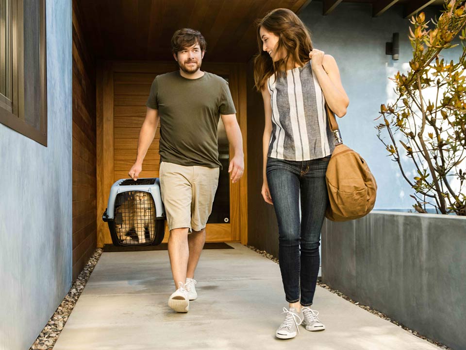 A man holding a cat in a carrier walking next to a woman