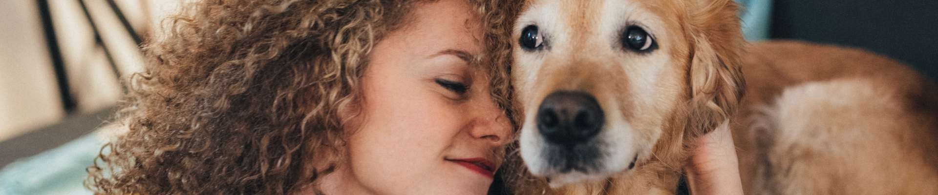 Una mujer mimando a su golden retriever de edad avanzada.