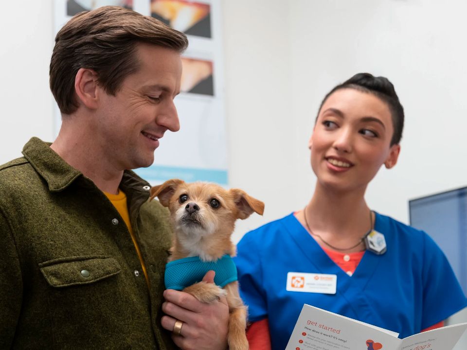hombre sostiene un perro mientras habla con el veterinario