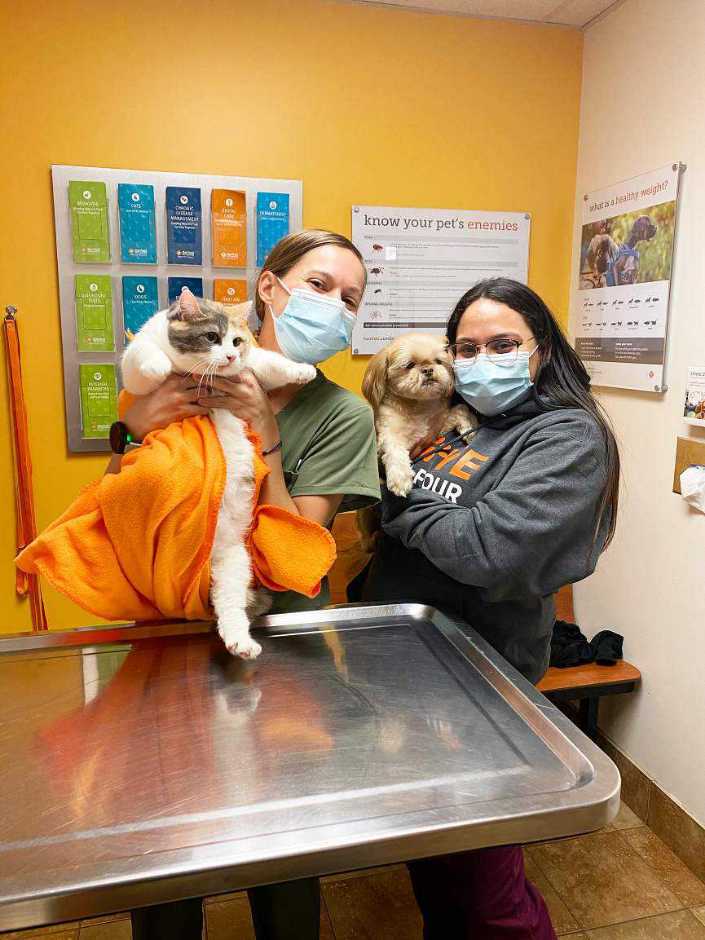 Un par de jóvenes asociadas sosteniendo a un perro y a un gato en Banfield Pet Hospital