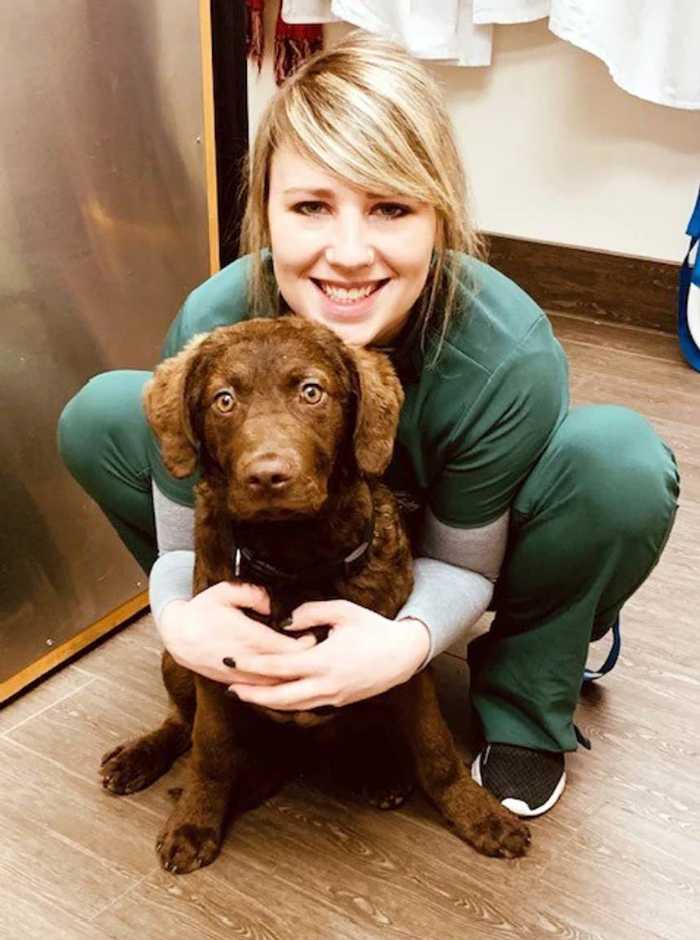 Una joven veterinaria sosteniendo a un perro marrón en Banfield Pet Hospital