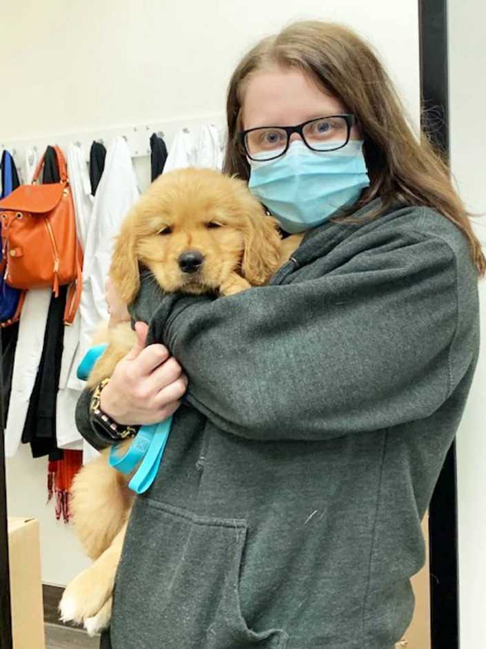 Una joven veterinaria abrazando a un cachorro en Banfield Pet Hospital